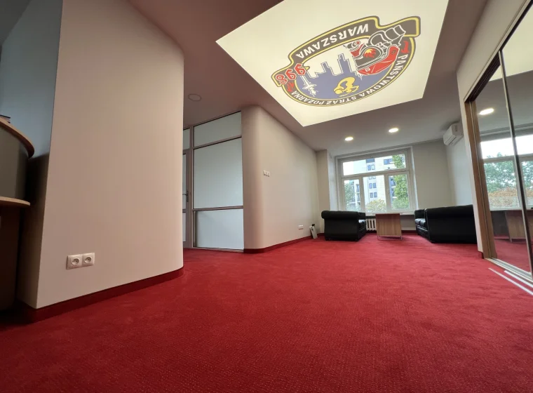 Korytarz w Państwowej Straży Pożarnej w Warszawie, czerwona elegancka jednolita wykładzina dywanowa oraz logo na suficie