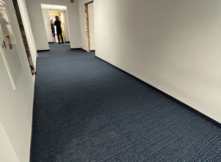 Granatowa wykładzina o linealnym wzorze na korytarzu w Instytucie Energetyki